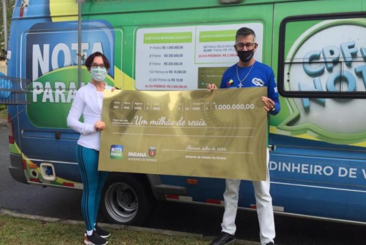 Ganhadores segurando o cheque de um milhão